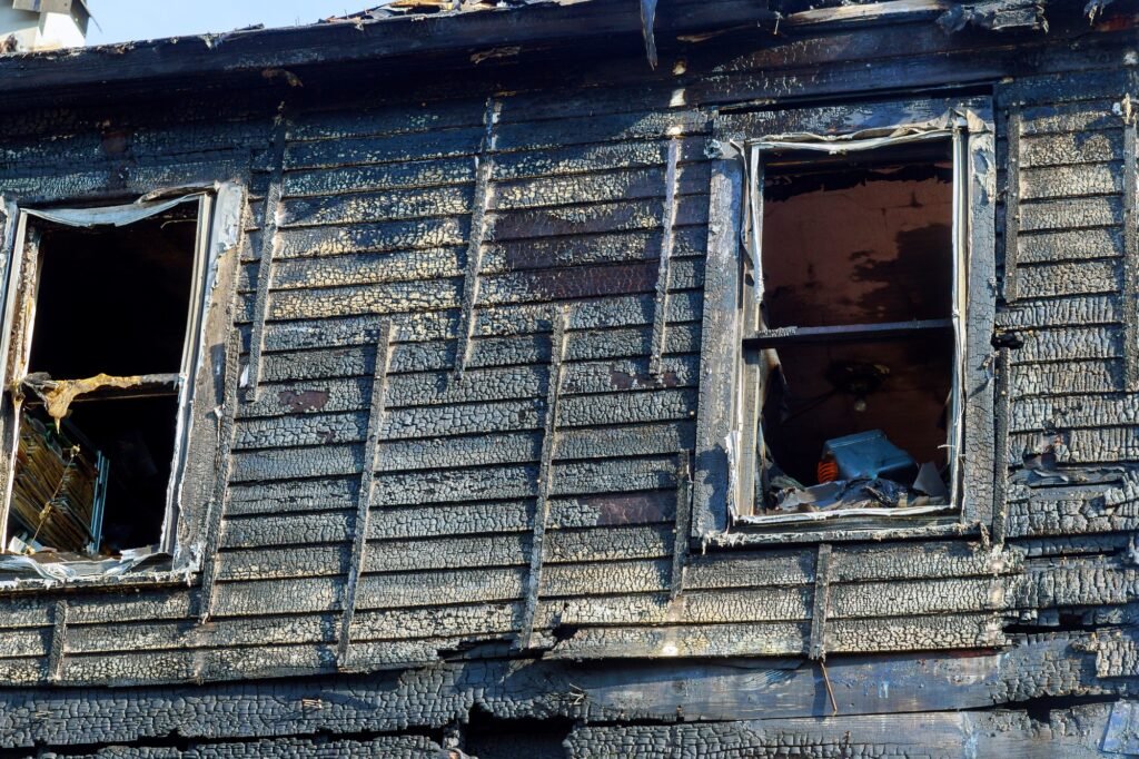 Burnt black house after fire line in front of a destroyed home.
